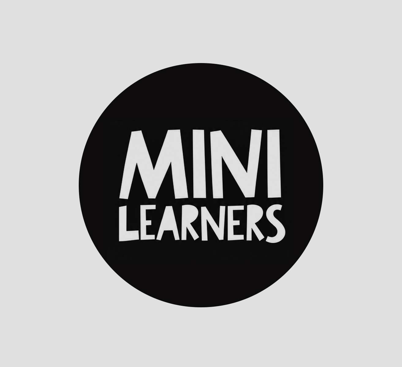 Mini Learners children's clothing, illustrated packaging and Little Big Ideas book in warm studio light.